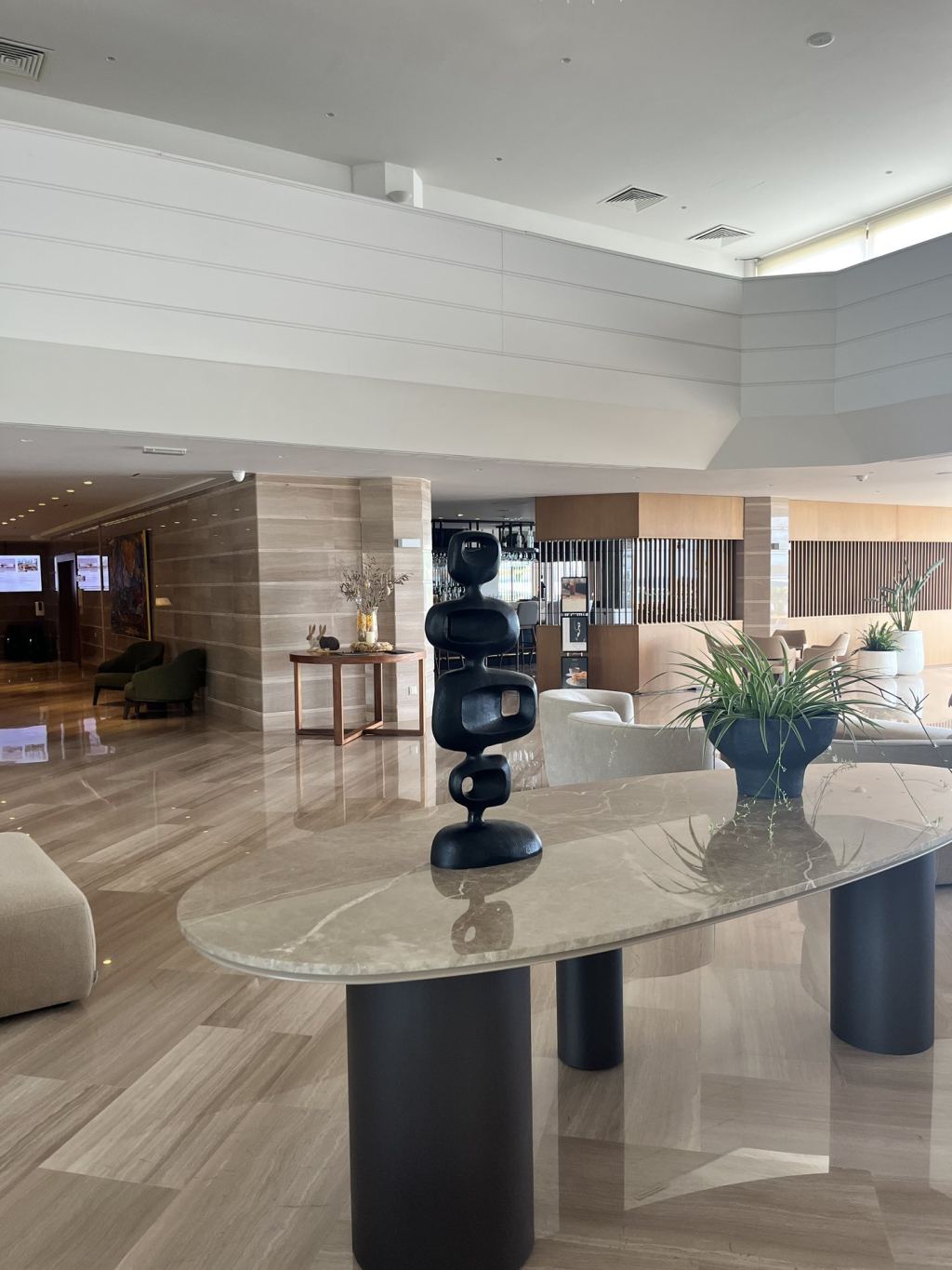 The bright lobby of the Alion Beach Hotel with natural stone and a modern sculpture