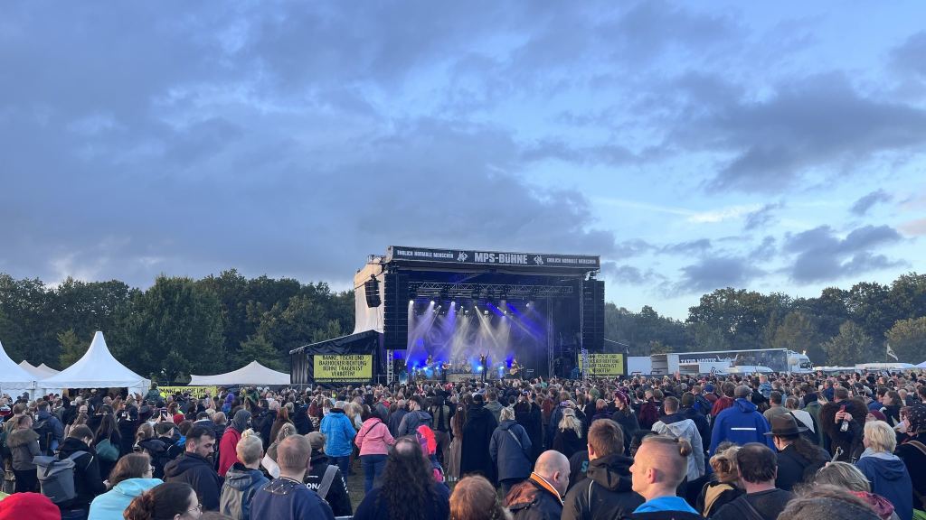 Publikum vor der MPS-Bühne im Abendlicht, auf der Bühne spielt eine Band