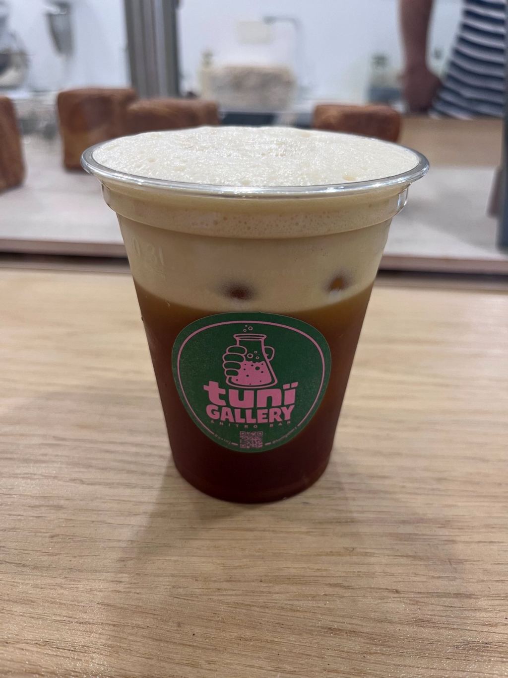 Cup of cold drip coffee with a pale foam head and the Tunï Gallery logo